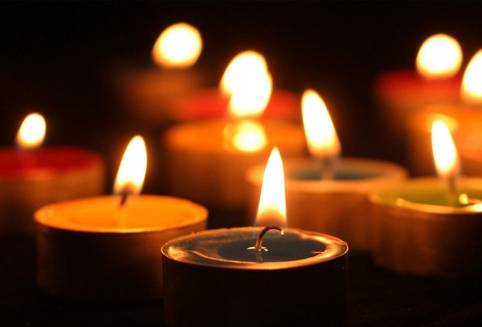 Image with a dark background, suggesting night time with several votive candles lit in a vigil or ceremony of some kind.