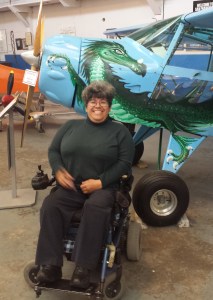 Alicia Contreras, sitting on her power chair next to a small plane at the airplane museum in Oakland, California. 