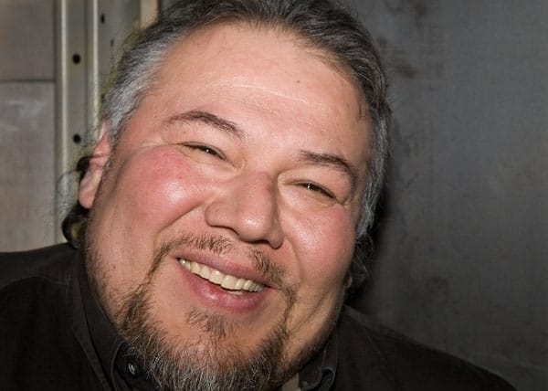 Jeff Thomas, an urban Iroquois man with brown hair with touches of gray and a beard. He is smiling at the camera. Photo credit: Justin Wonnacott