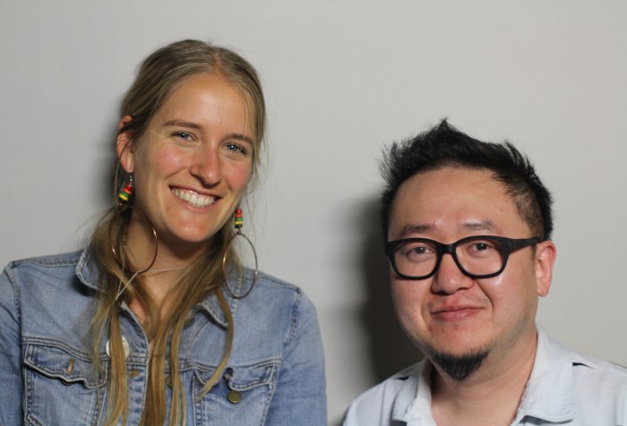 A photo featuring Steve Lee and Ali Murphy, taken on October 2nd, 2014. Ali Murphy is on the left, wearing a blue denim jacket and gold hoop earrings. Ali appears to be white with long blonde hair and blue eyes. She is smiling. Steve Lee is on the right, wearing dark framed glasses and a white collar shirt. He is Asian/American with short dark hair and dark colored eyes.