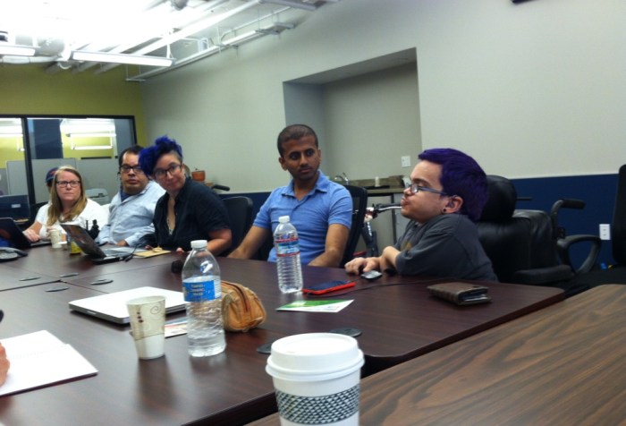Image of a group of people sitting in a conference room having a conversation on assistive technology