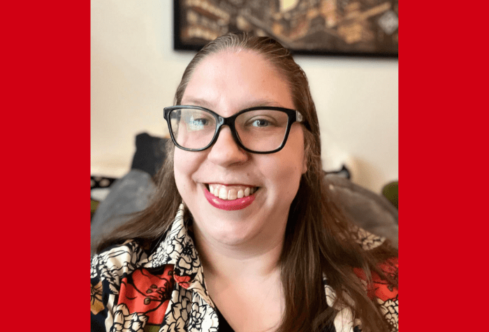 Graphic with a red background. Photo of Anna, a white nonbinary person with dark blond hair and glasses, smiling while sitting on a couch. They wear a black v-neck t-shirt and a floral print button down shirt.