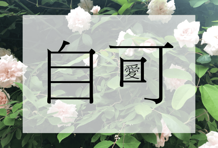 The Chinese character for self (自/zì) and the character in can (可/kě) with the traditional Chinese character for love (愛/ài) inside the character for mouth (口/ kǒu). The letters are black and are centred on a translucent white inset rectangular background in front of a background of an abundant bush of leaves and pink-white roses.