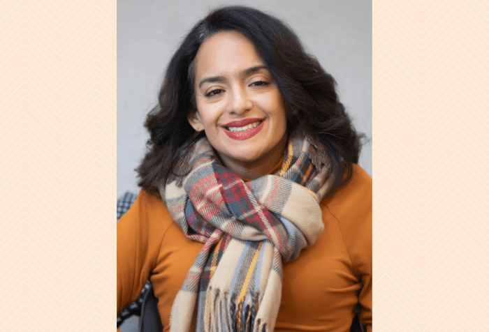 Graphic with a taupe background with a herringbone pattern featuring a photo of Ligia Andrade Zúñiga, a woman color with a disability smiling, she has long wavy hair, is wearing a scarf, and has long dangly earrings.