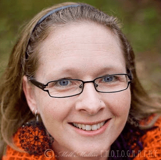Picture of a white woman with long blond hair held back with a headband. She is wearing glasses.